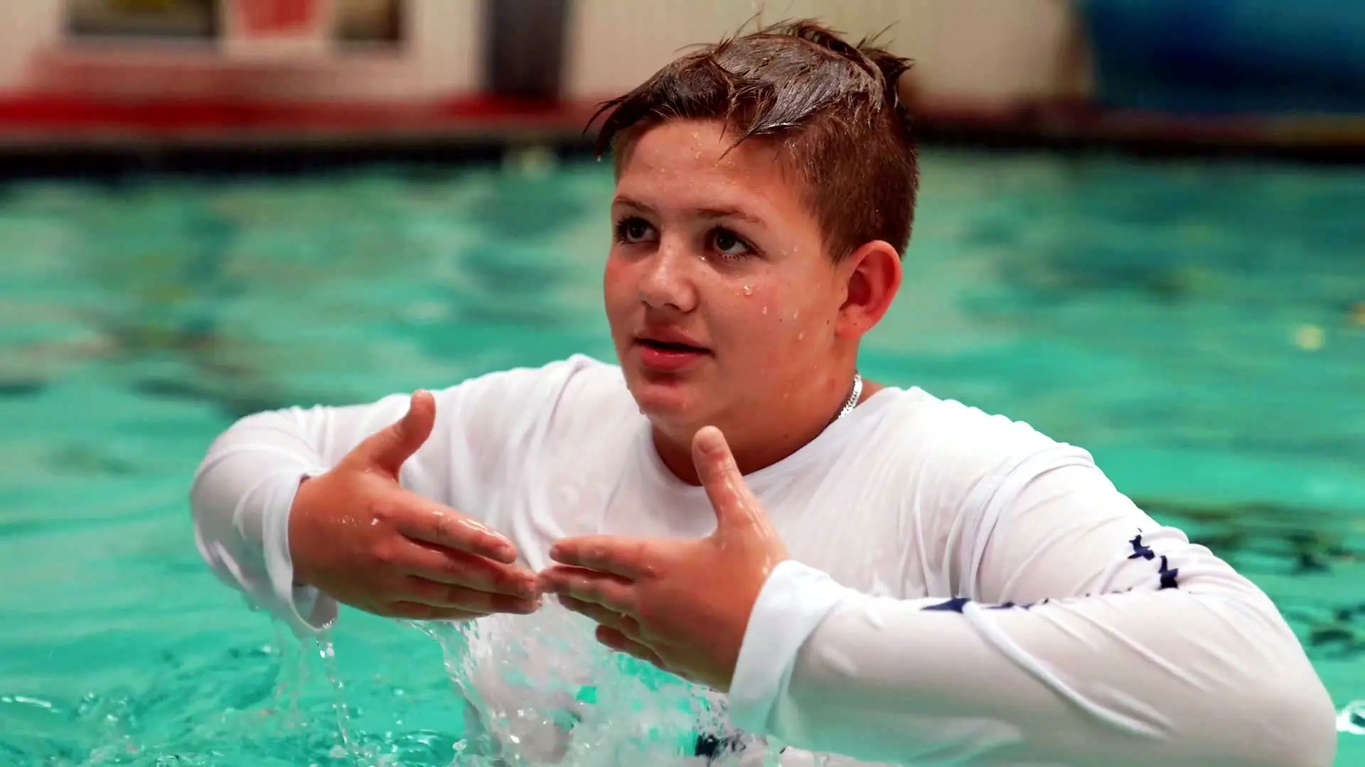 A young swimmer in a rash shirt listens during team practice