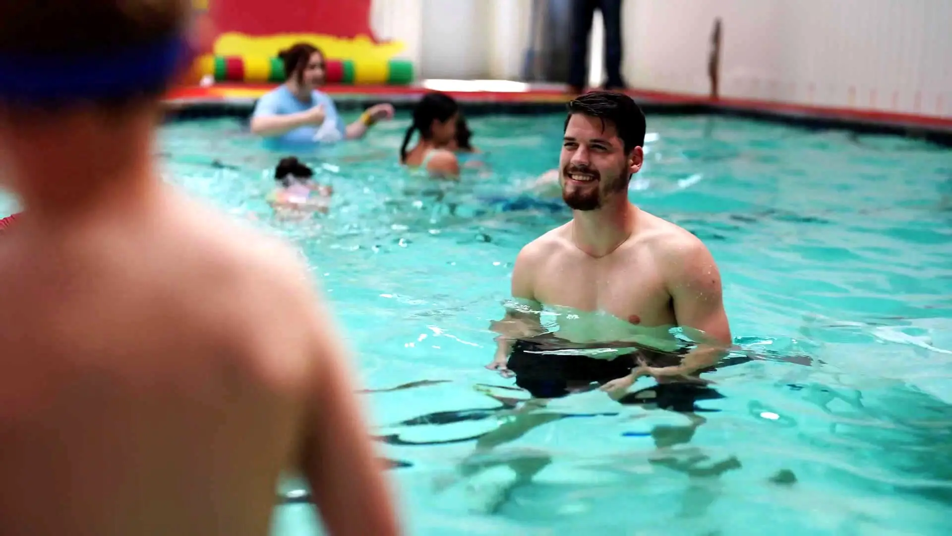 A Swimsational coach smiles at a swimmer during one-on-one instruction